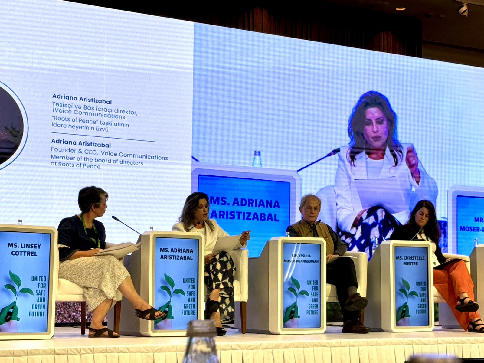 Adriana Aristizábal habla en un panel de la Conferencia Internacional sobre Acción contra las Minas en Bakú, con su imagen en la pantalla del escenario